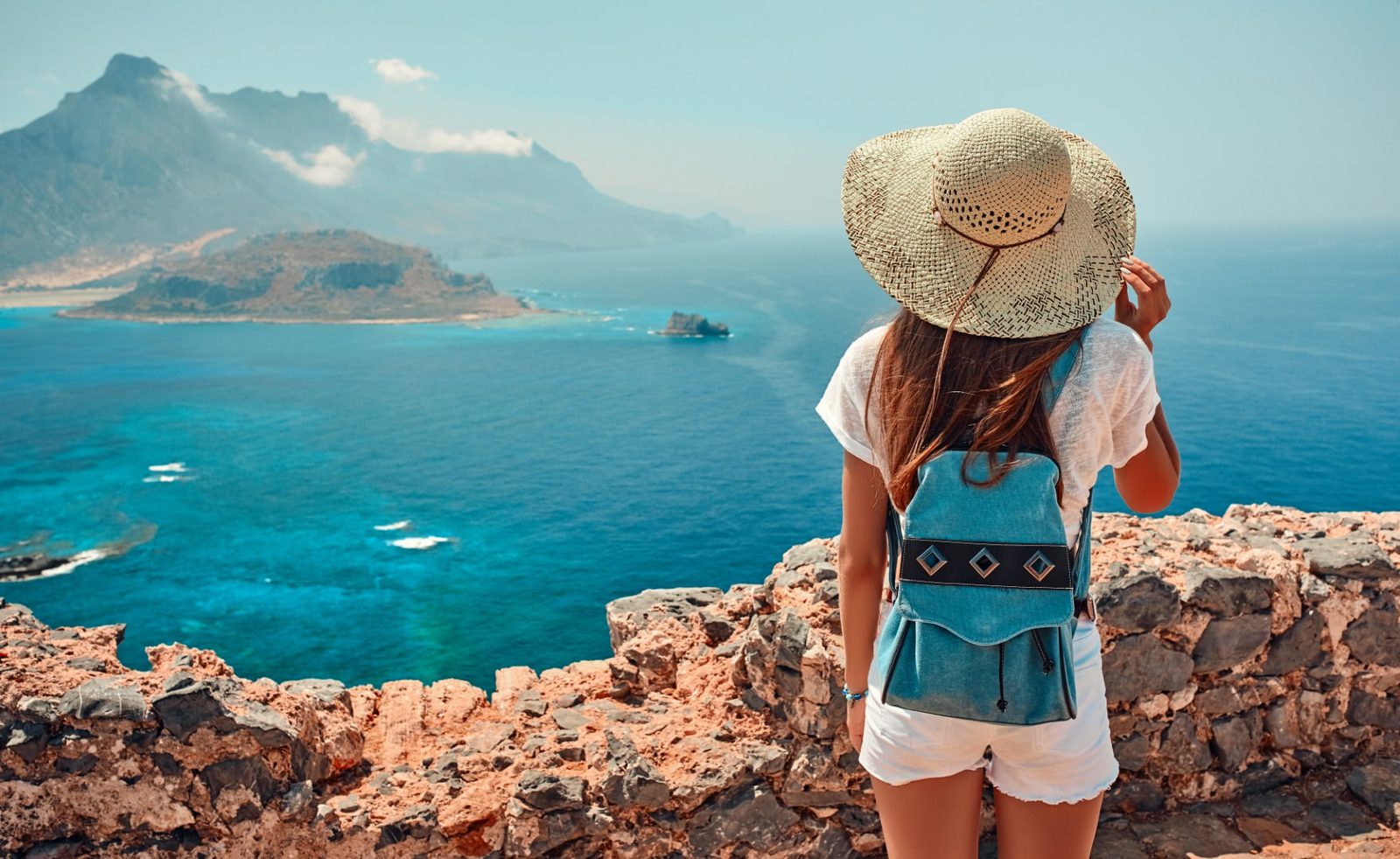 Traveler in a straw hat overlooking a turquoise island bay